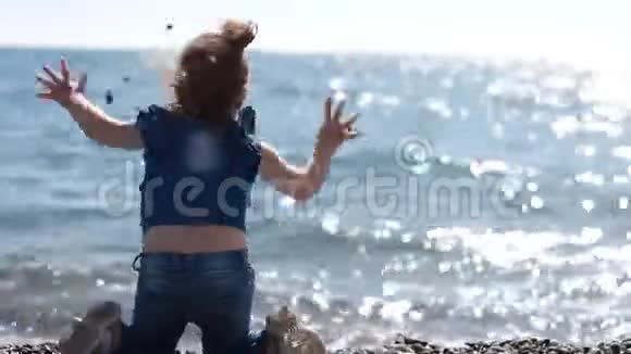 小女孩把石头从海岸扔进海水里视频的预览图