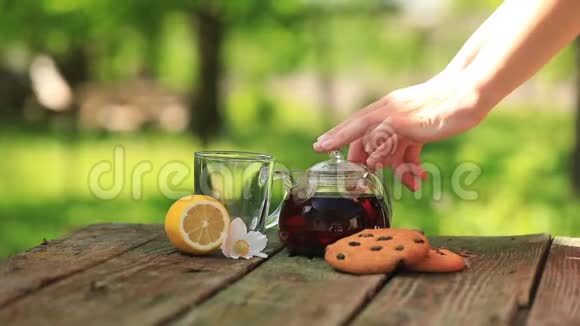 女人用透明茶壶冲泡红茶提供带饼干的大自然早餐视频的预览图