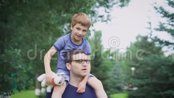 父亲送儿子回公园幸福的父亲让儿子骑在他的肩膀上仰望的肖像可爱视频的预览图