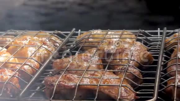 篝火的烟雾笼罩着烤鸡肉在烤架上烹饪视频的预览图