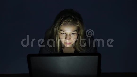 戴眼镜的女人在黑暗的房间里用电脑看着显示器开始高兴起来视频的预览图