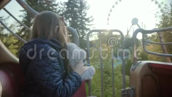 情绪愉快的小女孩与泰迪熊在旋转木马在夏天视频的预览图