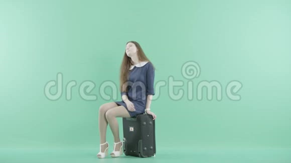一个穿着漂亮的女孩坐在手提箱上视频的预览图