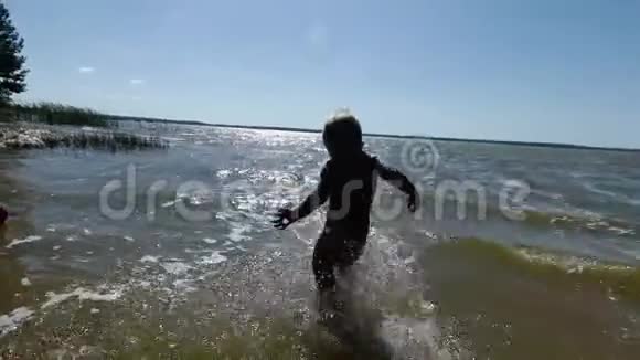 快乐的小男孩在水里溅起水花在湖里玩的孩子视频的预览图