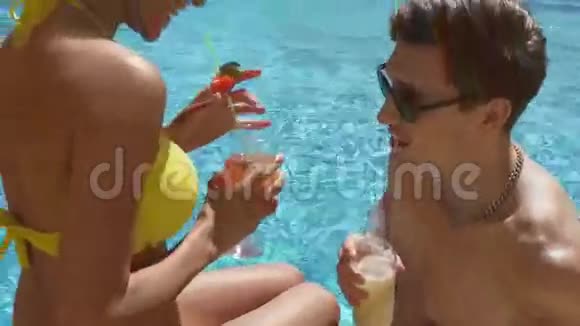 年轻的成年夫妇在游泳池里调情和交谈喝鸡尾酒发出欢呼声夏季游泳池视频的预览图