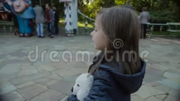 漂亮的女孩和她的朋友一只泰迪熊慢动作地在欢乐的公园里散步视频的预览图