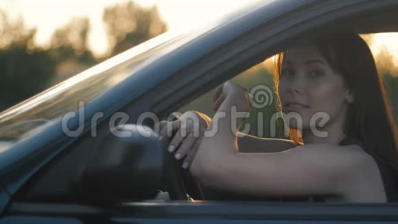夕阳背景下年轻女子坐在车里的画像视频的预览图