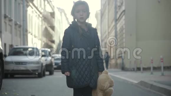 悲伤的小女孩带着泰迪熊呆在街上转身走开了视频的预览图
