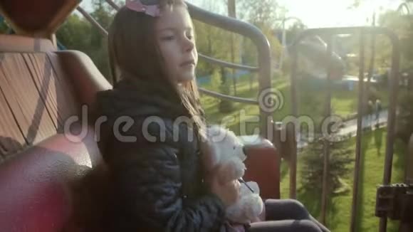 有趣的小女孩乘坐旋转木马在黄色的旋转木马车队公园视频的预览图