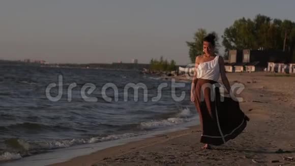 日落时分女人沿着海滩和大海散步视频的预览图