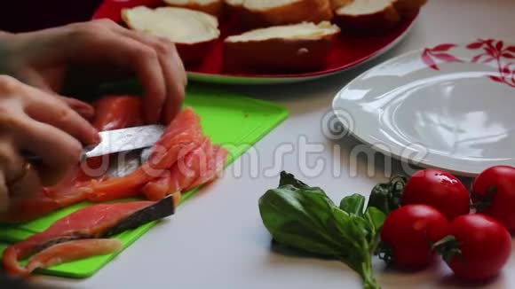 那个女孩正在准备三明治把三文鱼切片放在面包上白色背景的特写视频的预览图