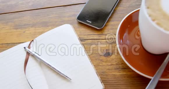 带有心形泡沫艺术的热咖啡拿铁杯带有日记和手机4k视频的预览图