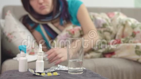 桌子椅子上的喷雾和水年轻的生病的女人在背景上为喉咙吃药视频的预览图