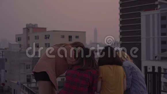 一群年轻的亚洲女性在屋顶上的日落都市晚会上随着DJ演奏的音乐翩翩起舞举起双臂视频的预览图