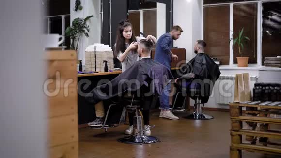 理发店内部形象和两个专业发型师女性和男性理发师与客户一起工作视频的预览图