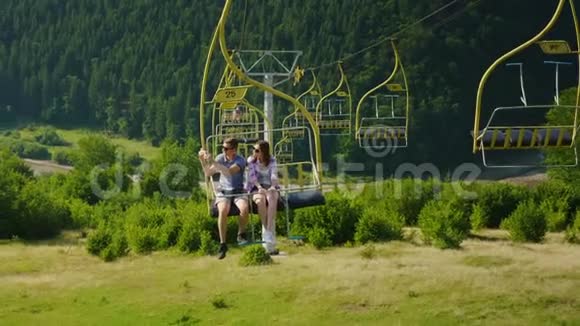 一对幸福的年轻夫妇正乘坐滑雪电梯拍摄风景夏天在山里度假视频的预览图