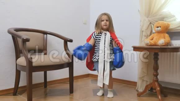 穿着红色斗篷戴着拳击手套的可爱小女孩展示了她的力量视频的预览图