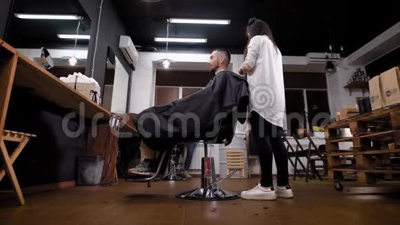 女青年理发师站在理发店边用梳子和剪刀做发型帅哥视频的预览图