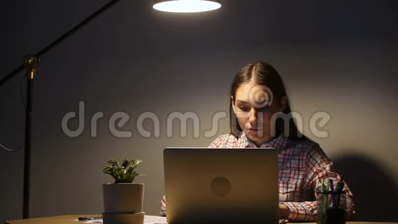 年轻女子在办公室工作到很晚手提电脑喝咖啡视频的预览图