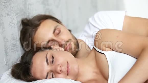 年轻夫妇睡在床上躺在白色亚麻布上拥抱视频的预览图