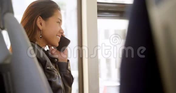 乘公共汽车旅行时使用手机交谈的少女视频的预览图
