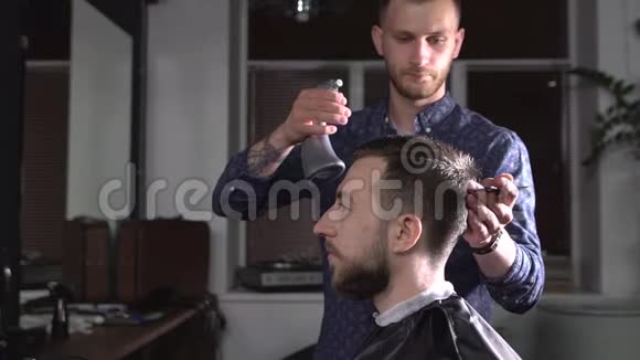 时尚男理发师的形象喷洒水在客户的头发并刷它使时尚的发型年轻的理发师视频的预览图