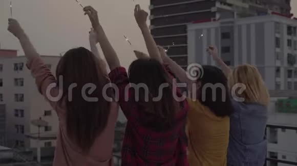 一群年轻的亚洲女性在屋顶上的日落都市晚会上随着DJ演奏的音乐翩翩起舞举起双臂视频的预览图
