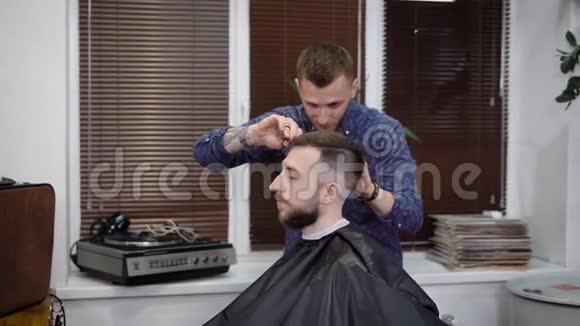 男理发师与客户一起工作用梳子和剪刀完美地塑造了他的发型女性视频的预览图