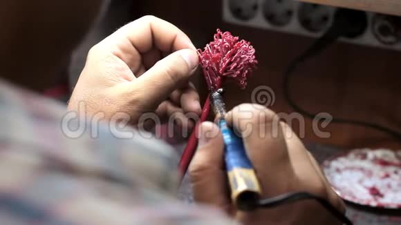 一个珠宝大师的特写镜头在放在一个烧瓶之前在一棵树上堆上珠宝的蜡坯选择性的聚焦视频的预览图