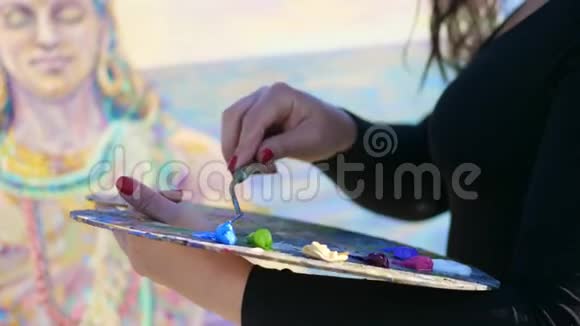 夏天户外特写女手的艺术家她用一个特殊的小铲把颜料涂在画布上视频的预览图