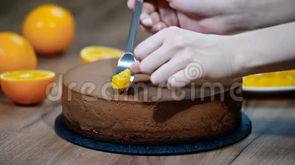 女人用手装饰的巧克力慕斯蛋糕和橙色的部分视频的预览图