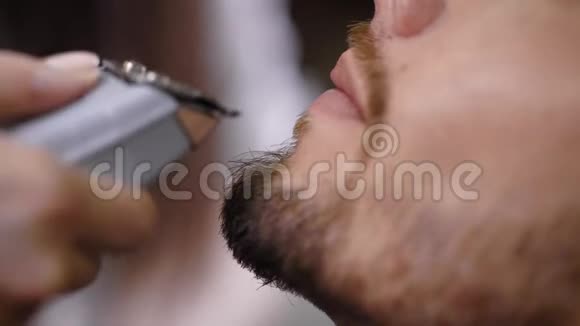 现代理发店的专业理发师给留胡子的男人做美容的形象靠近男性下巴视频的预览图
