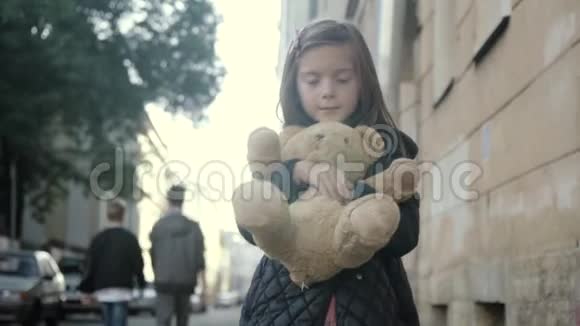 小女孩和她的玩具熊站在一起开心地微笑着在城市的小巷里视频的预览图