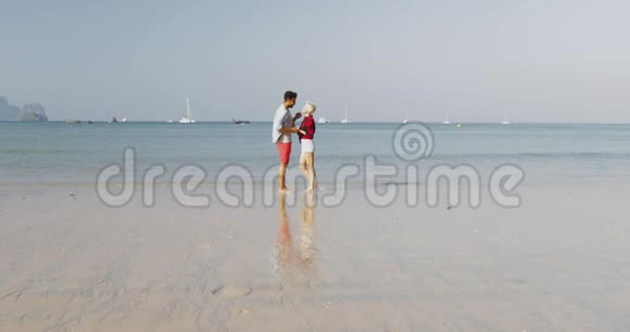 沙滩上的情侣牵手拥抱年轻的快乐游客在海上度假视频的预览图