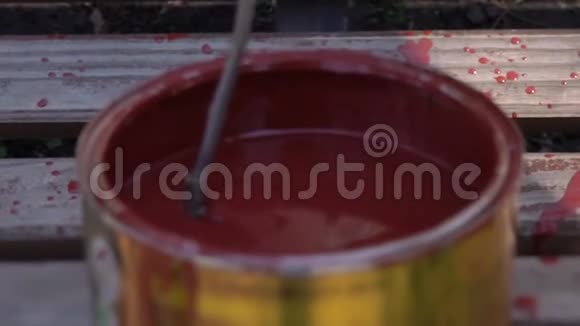 搅拌罐子里的红色油漆把油漆混合在木棍里慢动作视频的预览图