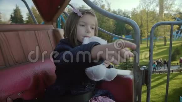 雪丽的女孩骑在一个环形交叉路口上看着她的泰迪熊在夕阳下的斯洛文尼亚转身视频的预览图