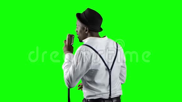 歌手从后面的视图唱成复古麦克风并在它附近跳舞绿色屏幕关门视频的预览图