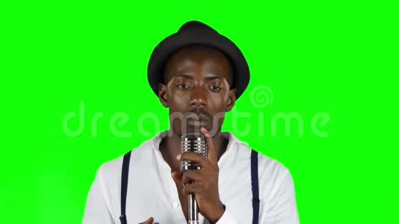 一个录音棚里的非裔美国人正在对着麦克风唱歌绿色屏幕关门视频的预览图