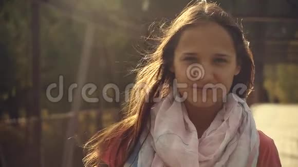 一位美丽的年轻女子在阳光下的肖像在风中长出头发视频的预览图