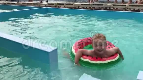 一个有充气圈的小男孩正在游泳池里游泳视频的预览图