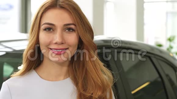 一位开朗迷人的女士微笑着在经销商处展示相机的汽车钥匙视频的预览图