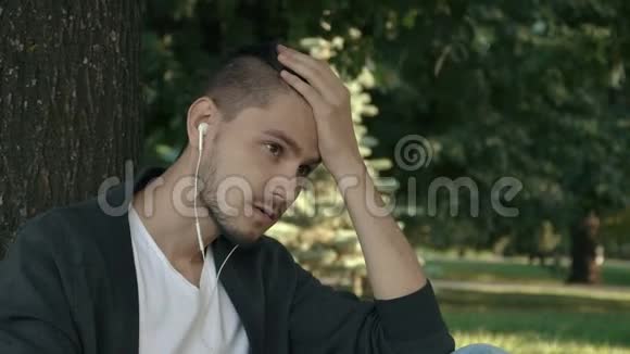 一个英俊而又疲惫的年轻人坐在树下视频的预览图