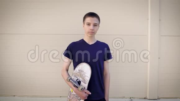 英俊少年站在街上手里拿着滑板的形象一个男孩花时间视频的预览图