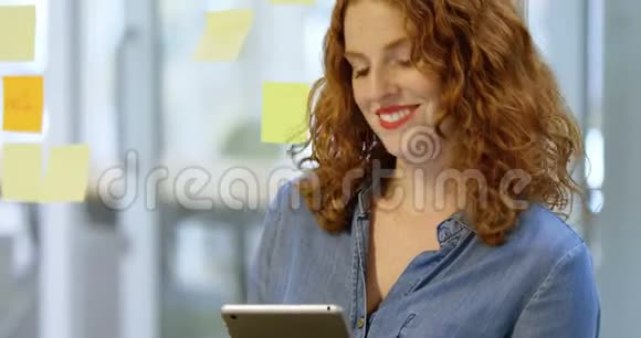 女商人正在读粘连笔记和数字平板电脑视频的预览图