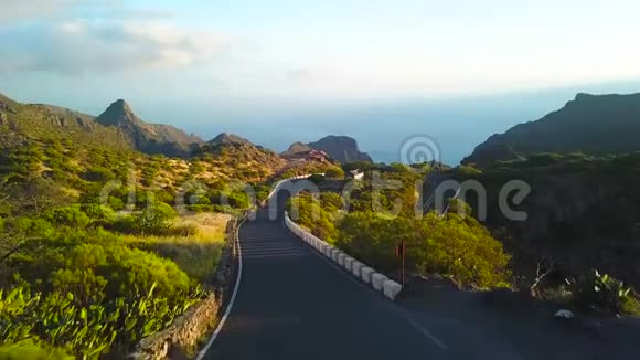 日落时分从远处马斯卡的岩石蜿蜒的道路和海洋的高度观看特内里费加那利视频的预览图
