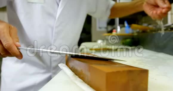 男厨师在厨房的磨石上磨刀视频的预览图