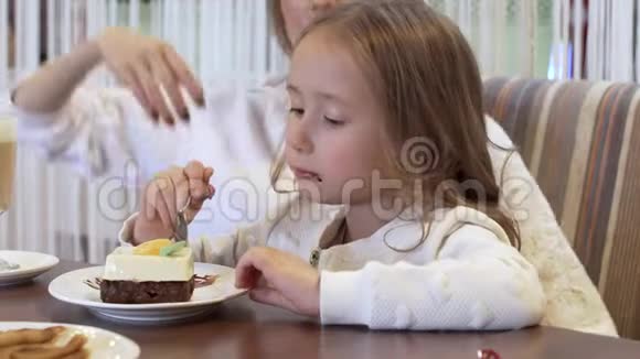 美丽的年轻妈妈和小女儿一起在舒适的咖啡馆里吃蛋糕视频的预览图