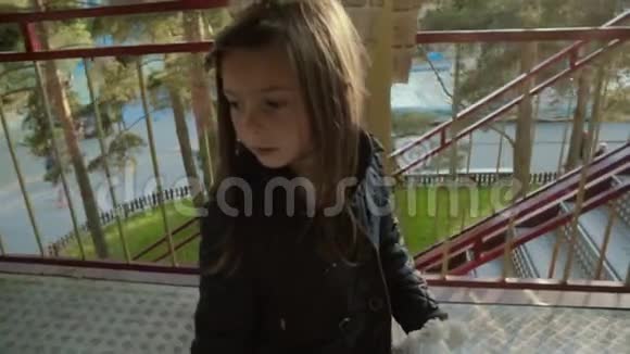 秋天小女孩在风景如画的公园里慢悠悠地走下楼梯视频的预览图