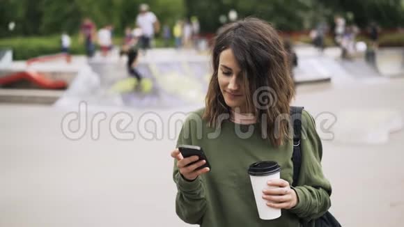 在滑板公园喝咖啡打电话的女人视频的预览图