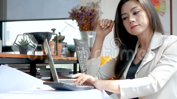 4K镜头忙碌的商务女性早上在城里的咖啡店里用笔记本电脑和计算器工作视频的预览图